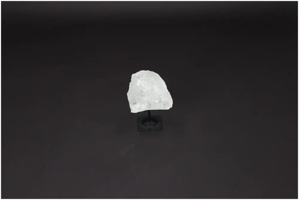 Lemurian Quartz on metal stand, showcasing a clear crystal known for clarity, balance, and personal growth in a minimalist setting.