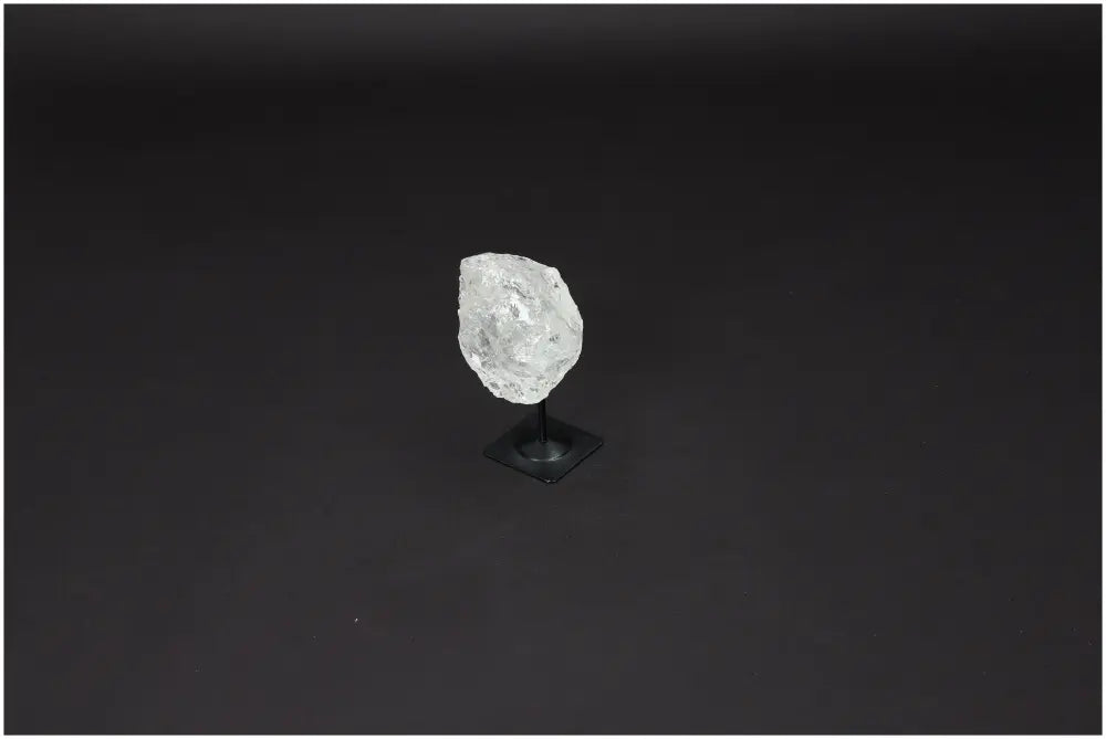 Lemurian Quartz crystal on metal stand, known for clarity and balance, showcased against a dark background.