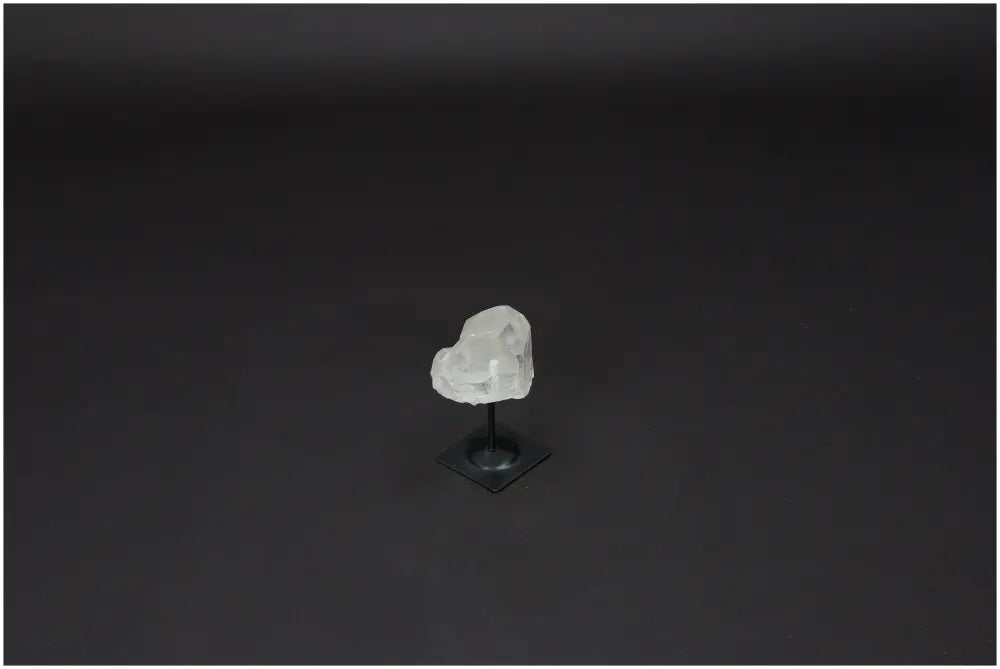 Lemurian Quartz crystal on metal stand, known for clarity and healing, displayed against a dark background.