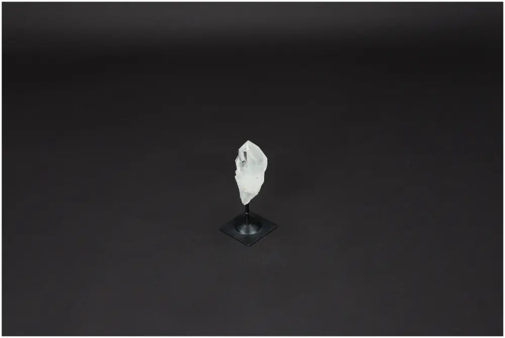Lemurian Quartz crystal on a metal stand against a dark background, showcasing clarity and healing properties.