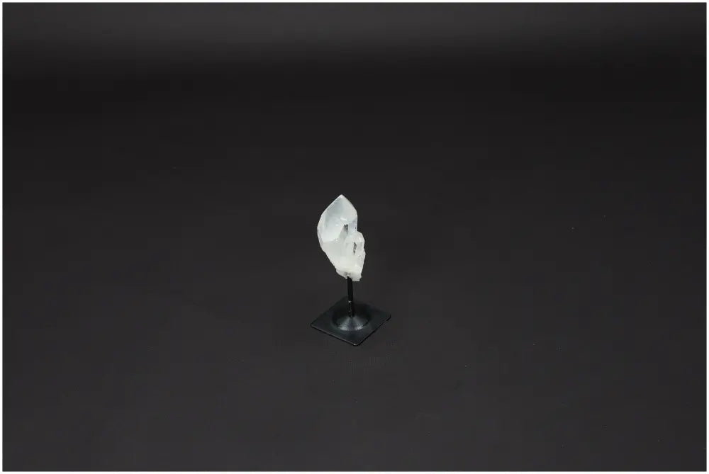 Lemurian Quartz on metal stand displaying a clear quartz crystal, symbolizing clarity and personal growth, on a dark background.