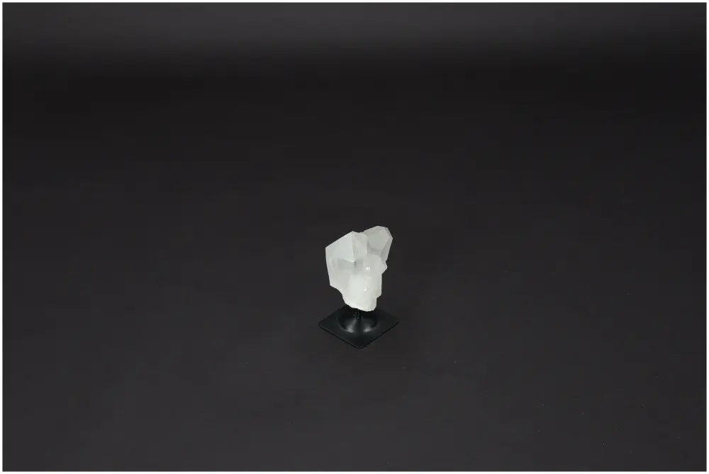 Lemurian Quartz on metal stand, clear quartz crystal for purification and energy harmonization, against a dark background.