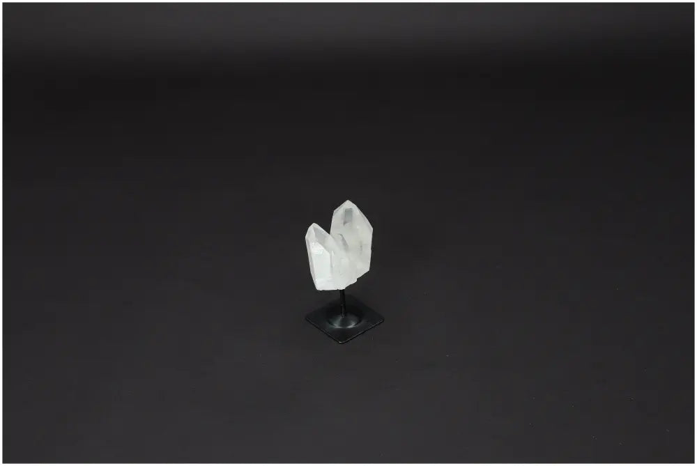 Lemurian Quartz crystal on black metal stand, known for purifying and harmonizing energy, against a dark background.