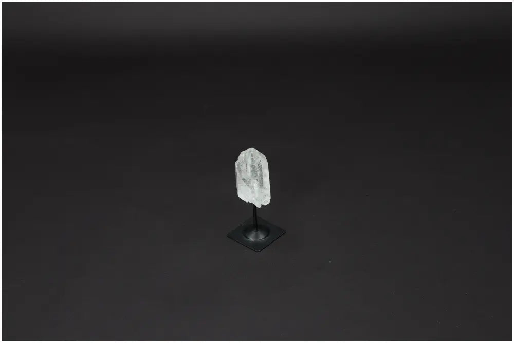 Lemurian Quartz on metal stand against dark background, promoting purification and harmony, ideal for neutralizing negative energies.