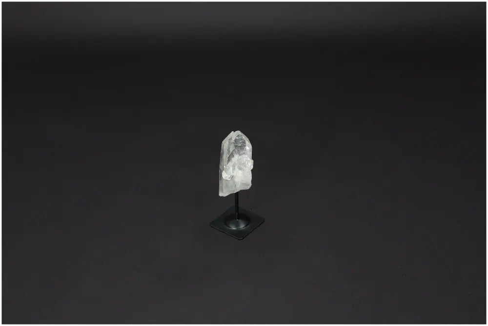 Lemurian Quartz crystal on metal stand against dark background, known for purification and neutralizing negative energy.
