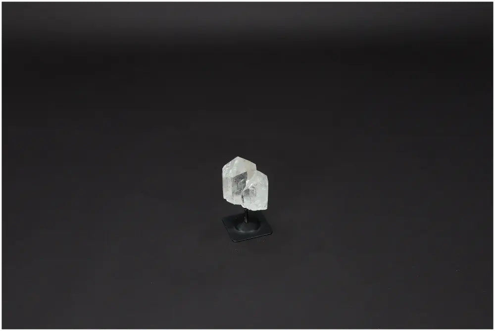 Lemurian Quartz crystal on metal stand against a dark background, known for harmonizing energy and neutralizing negative vibrations.