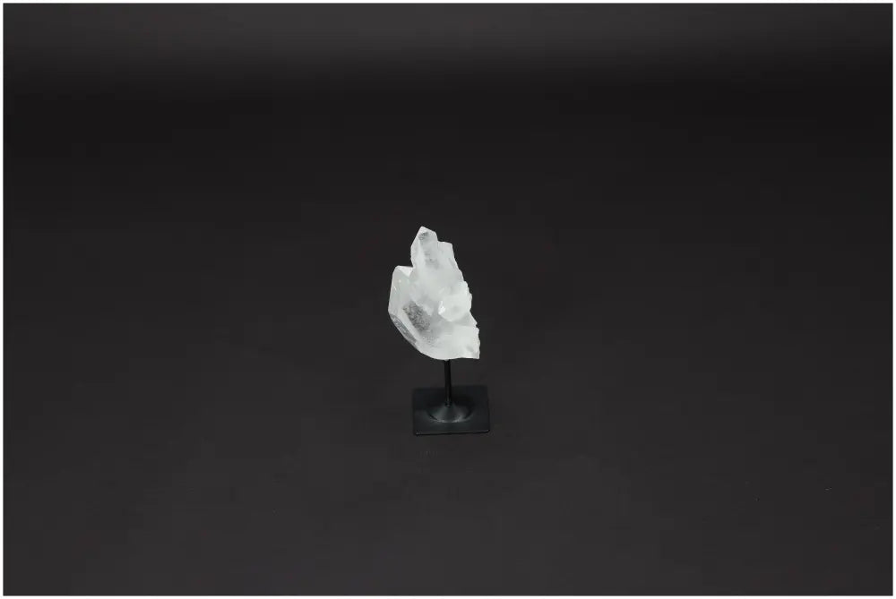 Lemurian Quartz crystal on a metal stand against a dark background, known for its purification and harmonizing properties.