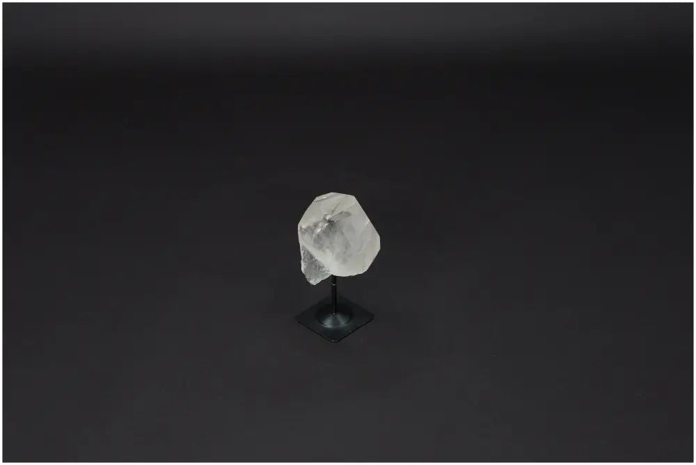 Lemurian Quartz crystal on black metal stand, known for purification and neutralizing negative energy, against a dark background.