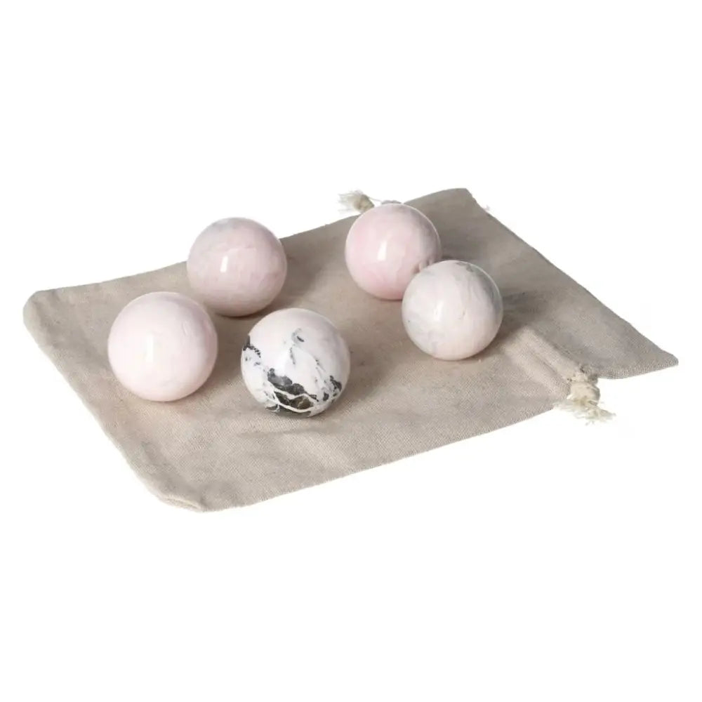 Collection of manganocalcite spheres on a beige cloth, known for healing properties and enhancing creativity.