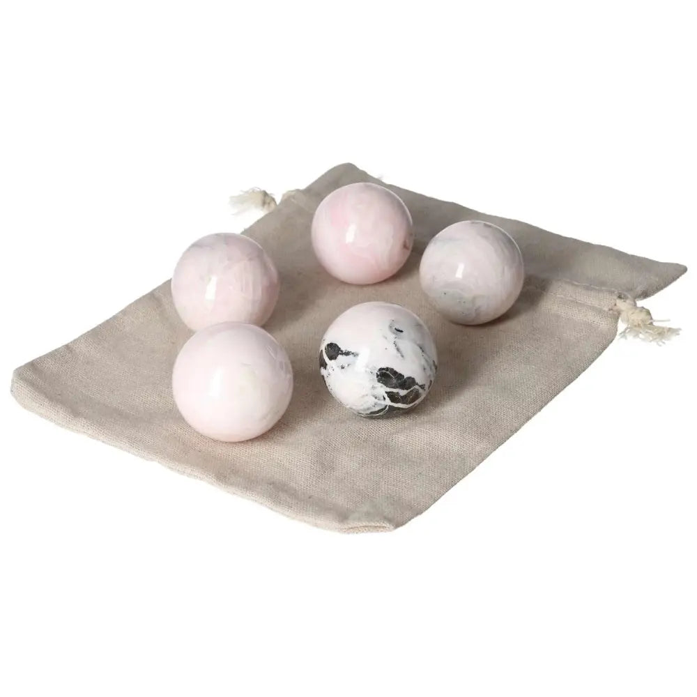 Five Manganocalcite spheres on a beige cloth, known for healing and boosting creativity.