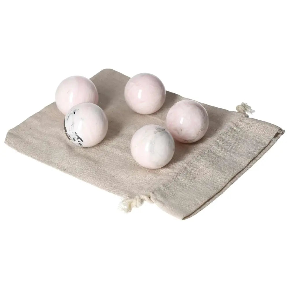 Set of pink Manganocalcite spheres on a beige cloth, known for healing, creativity boost, and promoting peace and calm.