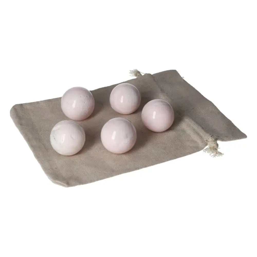 Five pink manganocalcite spheres displayed on a beige cloth, promoting healing, peace, and creativity.