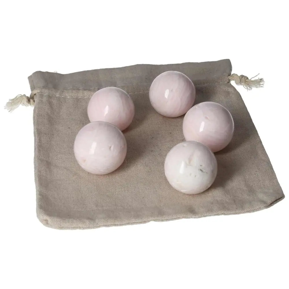 Mangano calcite spheres on a beige pouch, known for healing properties, creativity boost, and promoting peace and calm.