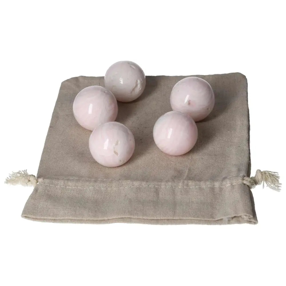 Five Manganocalcite spheres on a beige cloth bag, promoting calm and creativity.