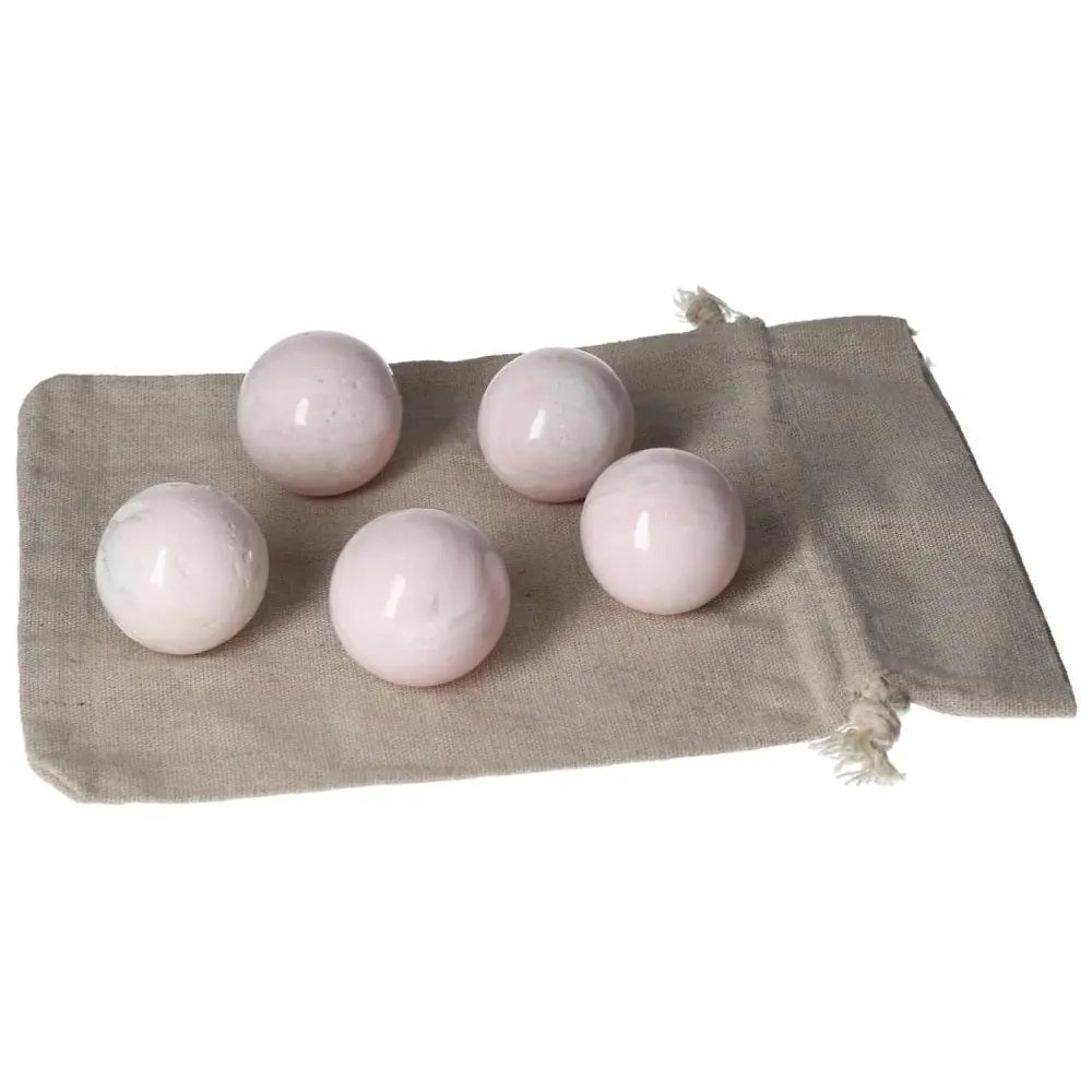 Five small manganocalcite spheres on a cloth bag, known for promoting peace and boosting creativity, perfect healing crystals.