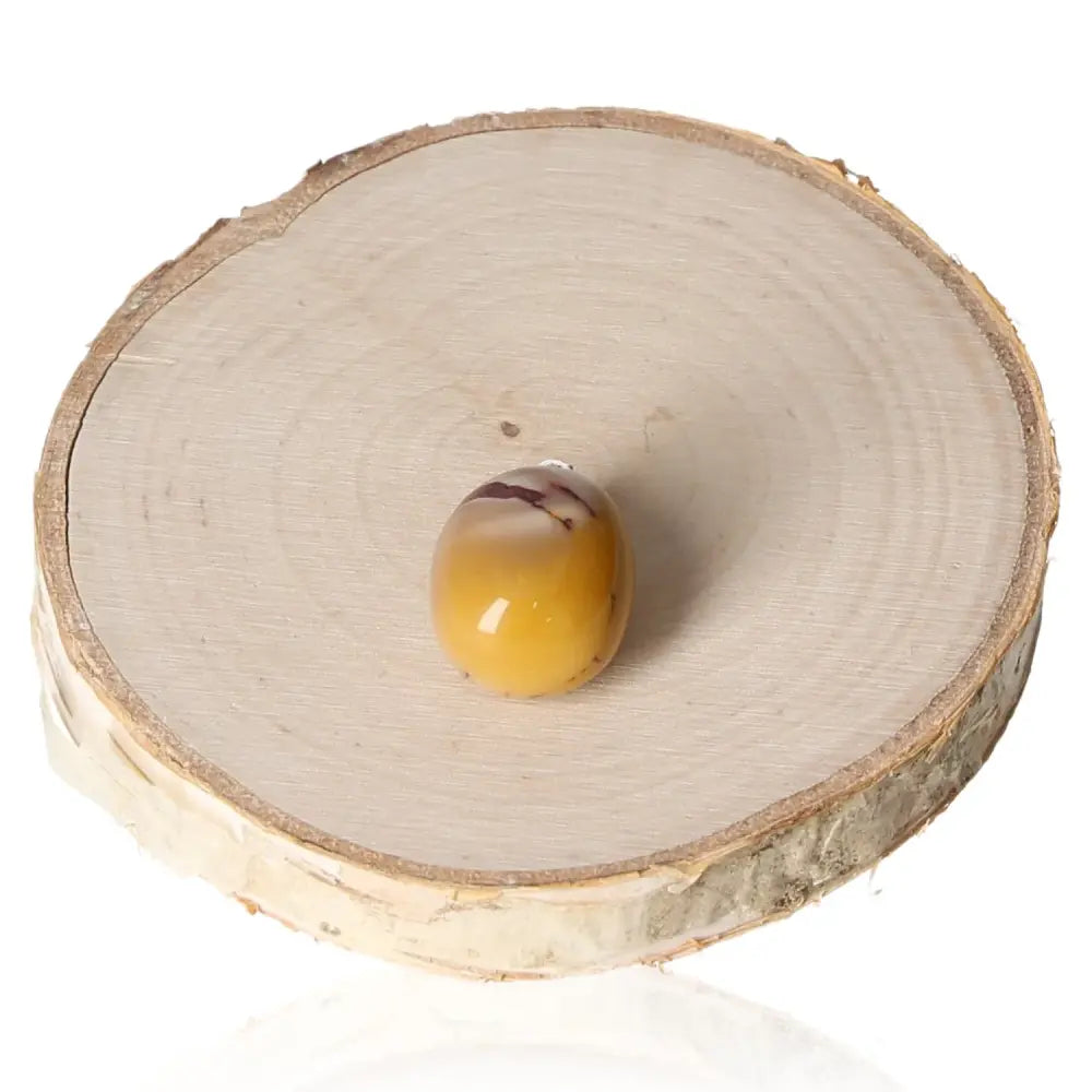 Mookaite Yellow Tumbled Pendant resting on wood slice, showcasing unique mustard and burgundy tones of natural gemstone jewelry.