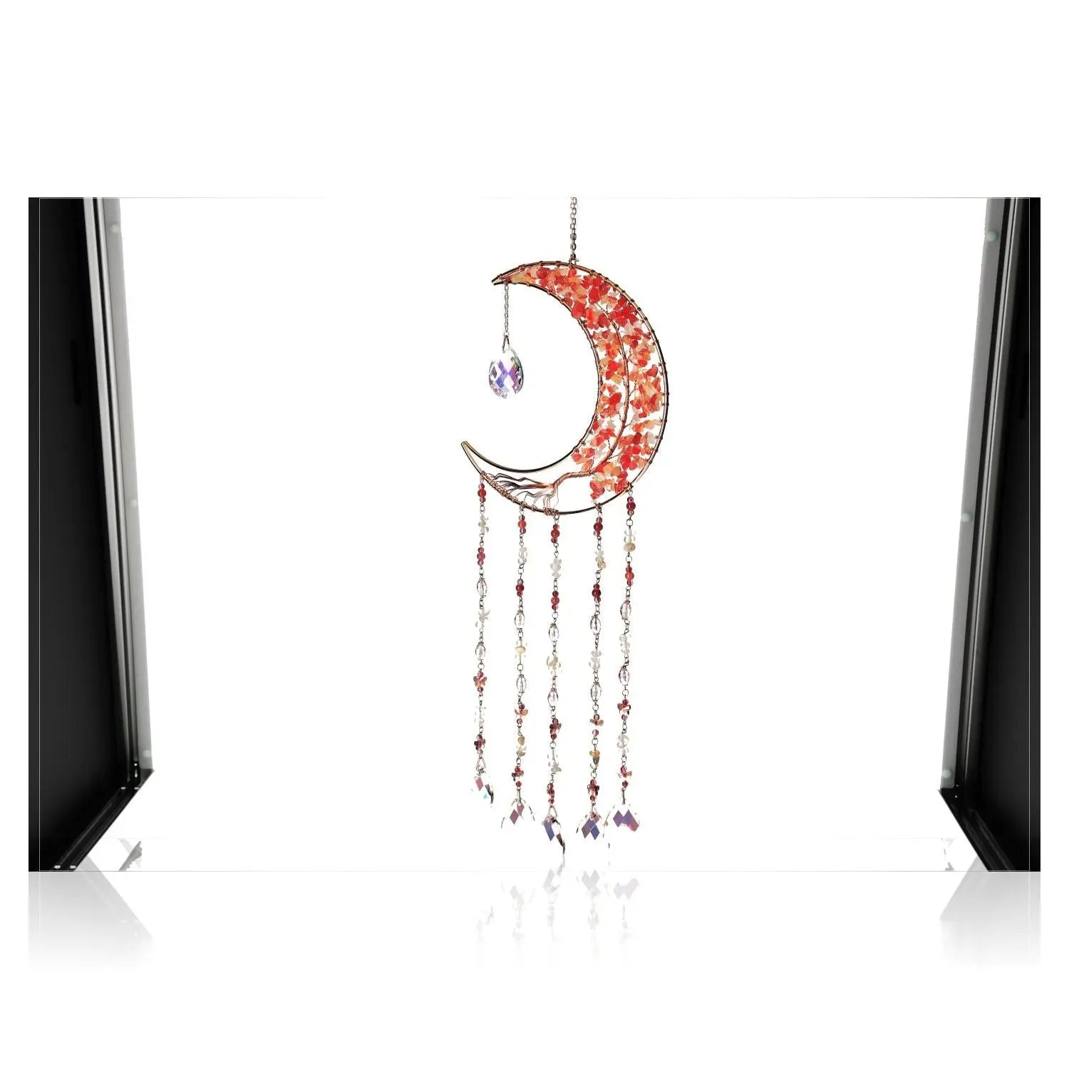 Moonlight Suncatcher with Red Agate crystal, crescent shape, and dangling chains, casting vibrant reflections in a bright space.