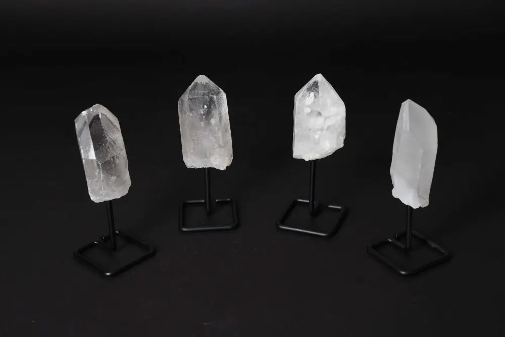 Natural clear quartz points with stands, known for energy amplification and clarity, elegantly displayed against a dark backdrop.
