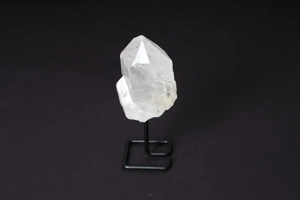 Natural Clear Quartz Point on stand for clarity and energy alignment, ideal for meditation and manifestation, shown against dark background.