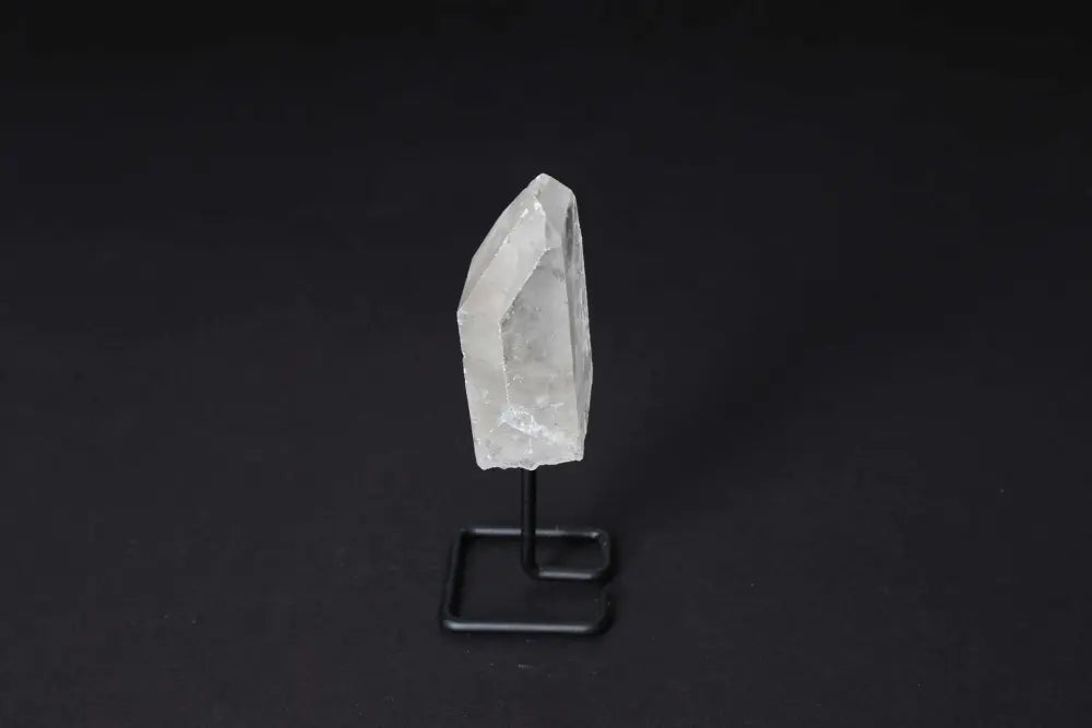 Clear Quartz Point on stand, amplifying energy for meditation and clarity, displayed against a dark background.