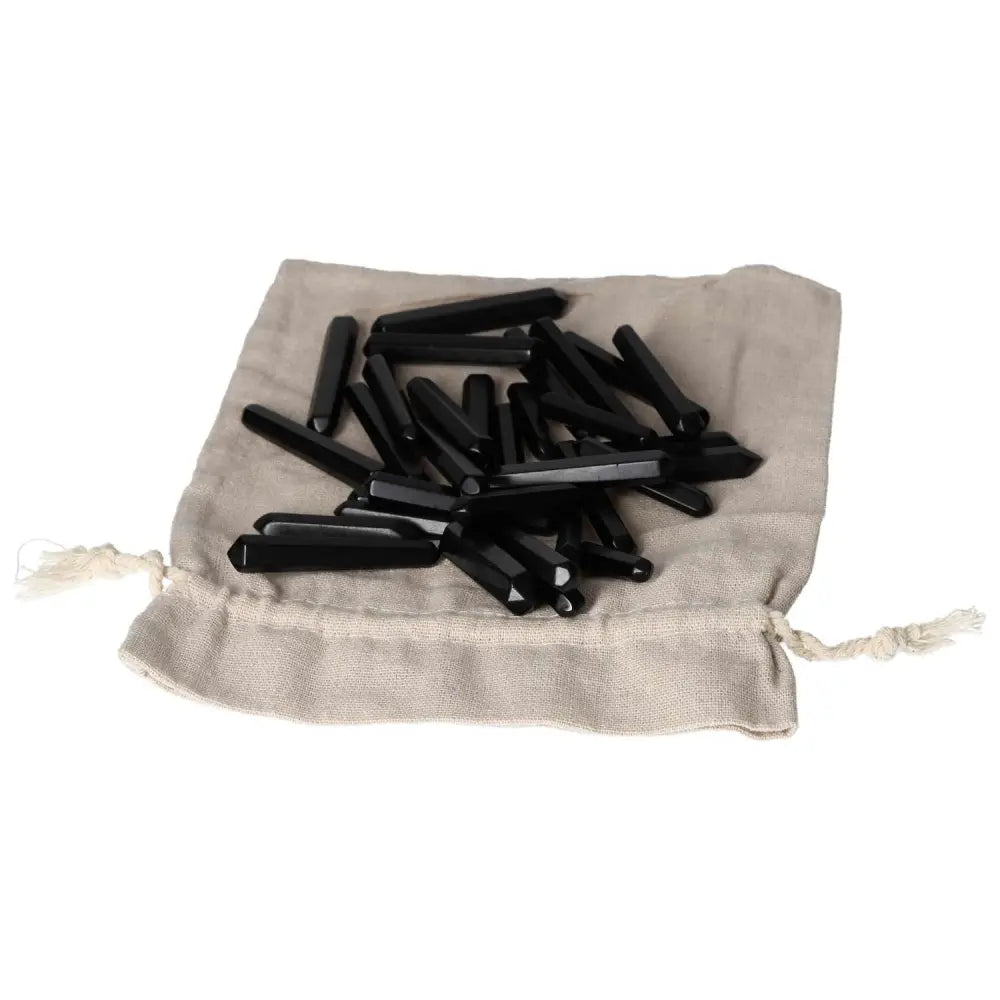 Collection of Obsidian Small Sticks on a beige fabric pouch, showcasing the protective properties of this mineral against negative energies.