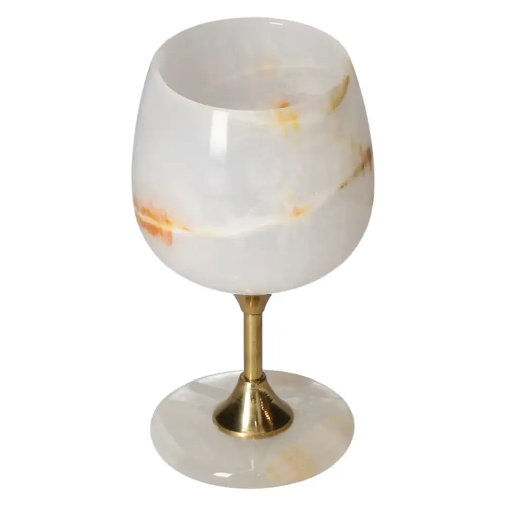 Exquisite off-white onyx wine glass with natural veining and a polished surface, set on a gold stem, ideal for elegant occasions.