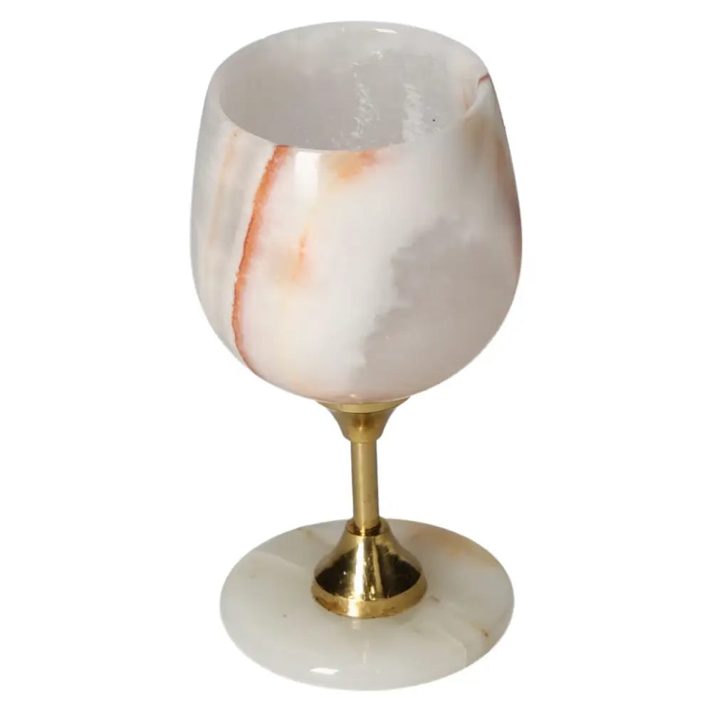 Elegant onyx wine glass with unique color veining, polished off-white surface, and gold stem, exuding sophistication for fine dining.