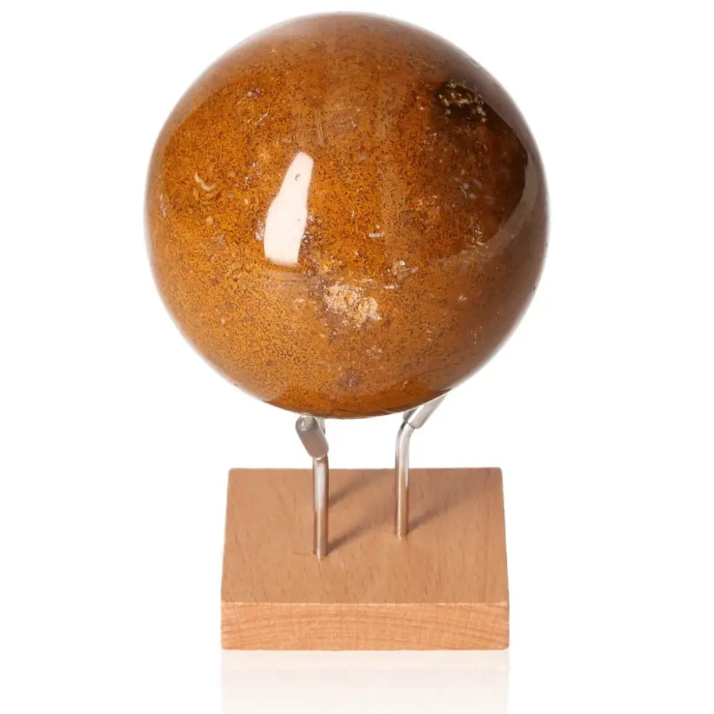 Brown gemstone sphere on wooden stand, ideal for home decor and energy healing practices.