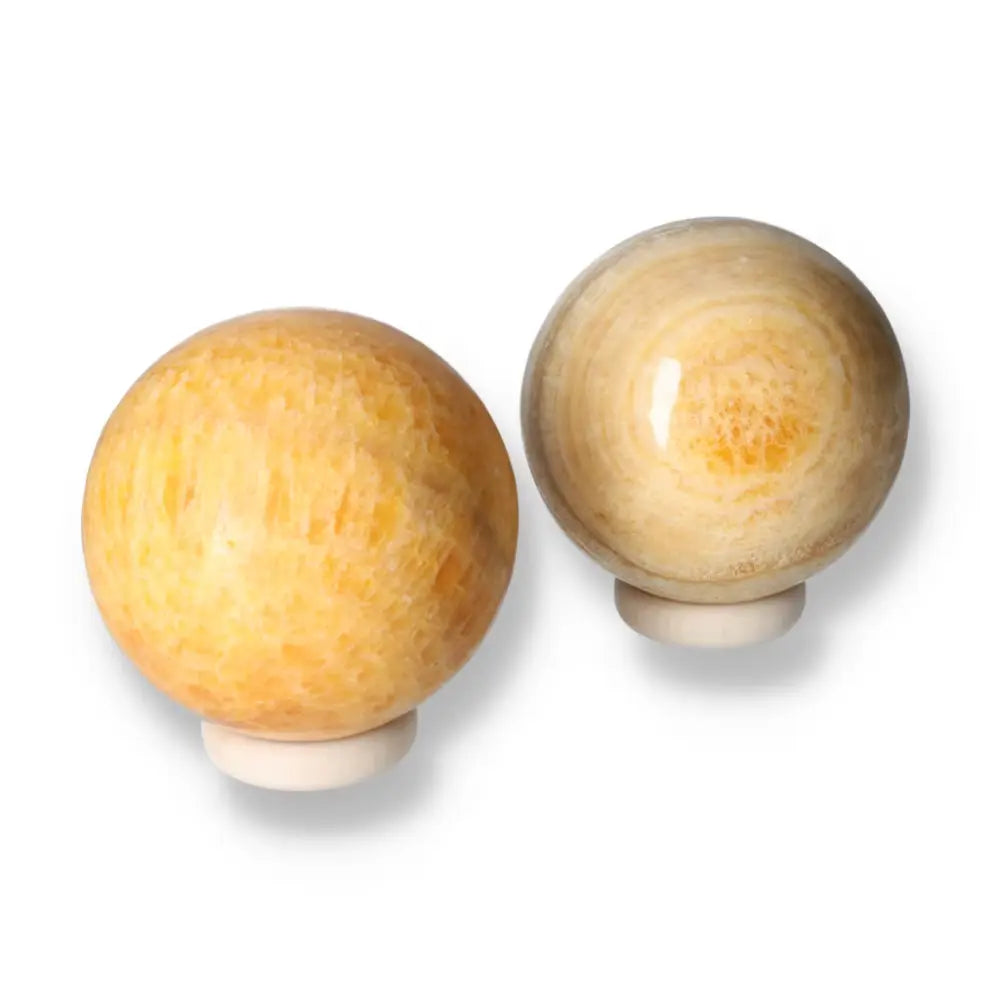 Two polished orange calcite spheres on stands, showcasing vibrant and warm hues, perfect for enhancing positivity and creativity.