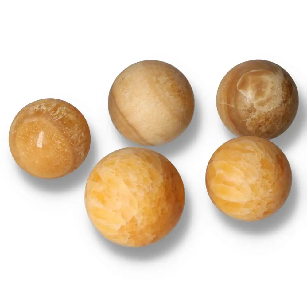 Five polished orange calcite spheres, known for vibrant energy and positivity, displayed on a white surface.