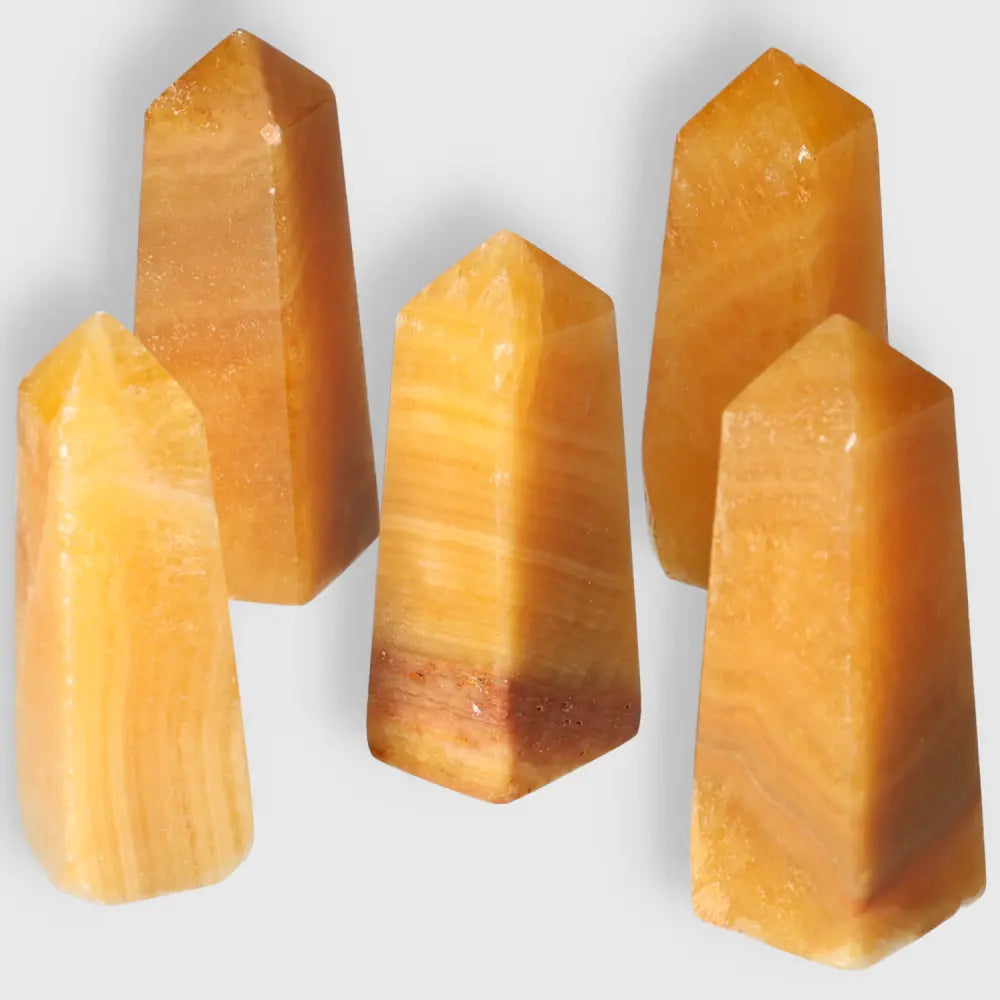 Orange Calcite Tower M for emotional healing, creativity, and positivity. Polished crystal with vibrant hues and pointed shape.