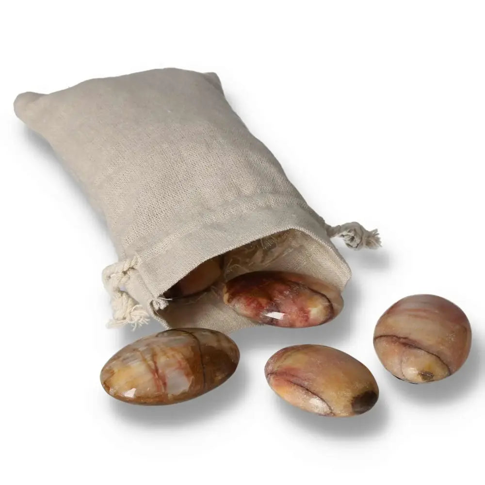 Peach Calcite Palm Stones spilling from a beige pouch, showcasing their polished surface, perfect for meditation and emotional healing.