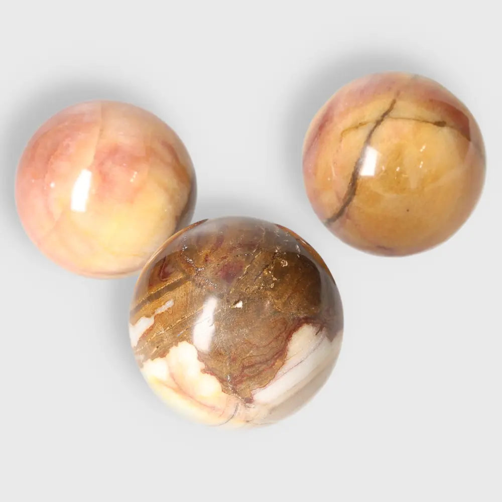 Three polished peach calcite spheres radiating warmth and balance, ideal for crystal collections or gifting purposes.