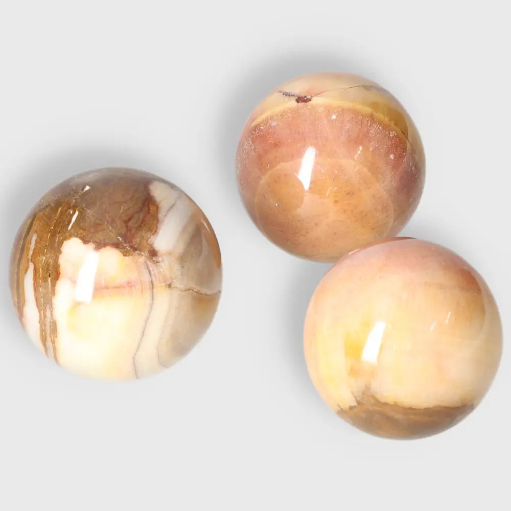 Three polished Peach Calcite Spheres radiating warmth and balance, ideal for emotional healing and crystal collections.