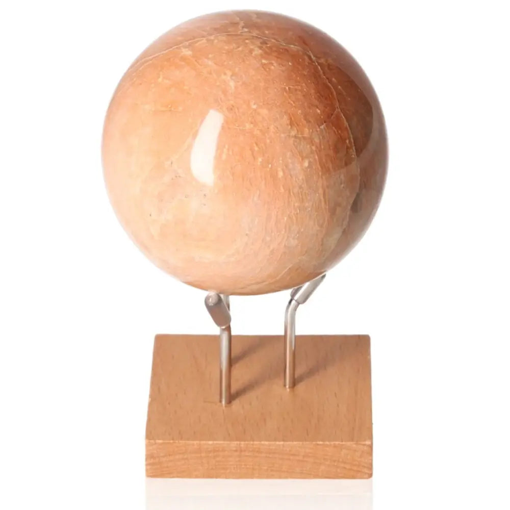 Peach Moonstone sphere on stand, known for calming, soothing properties and promoting inner peace and emotional healing.