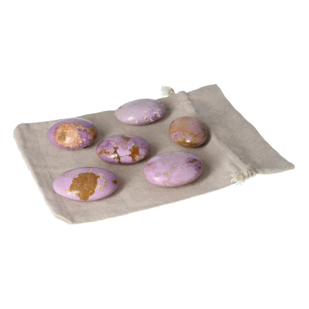 Phosphosidente palmstones in various shades of purple and gold on a beige cloth bag, enhancing energy and well-being.