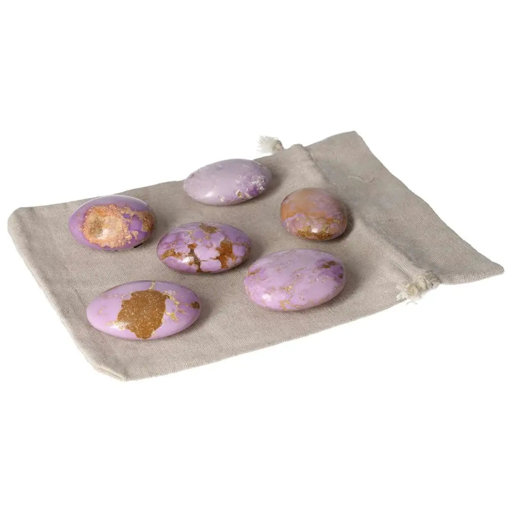 Phosphosidente palmstones displayed on a beige pouch, featuring smooth oval shapes in purple hues with golden accents.