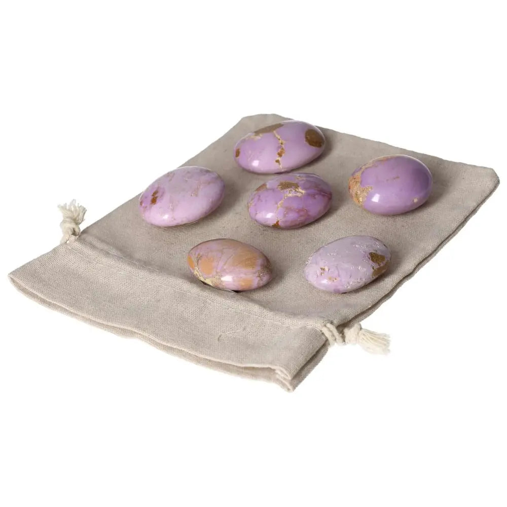 Collection of Phosphosidente palmstones displayed on a beige cloth, featuring unique pink and purple hues with natural markings.