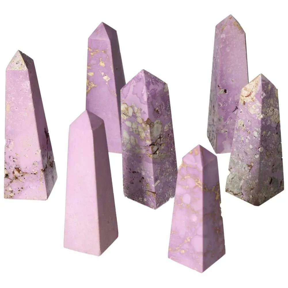 Collection of purple gemstone obelisks showcasing various marbling patterns and shades, standing against a white background.