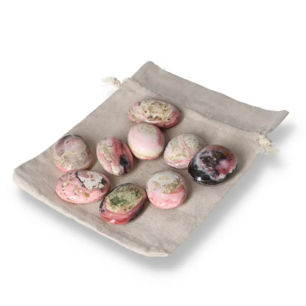 Pink Opal palmstones in a beige pouch, showcasing soft pink hues and opalescent sheen for emotional healing and personal transformation.