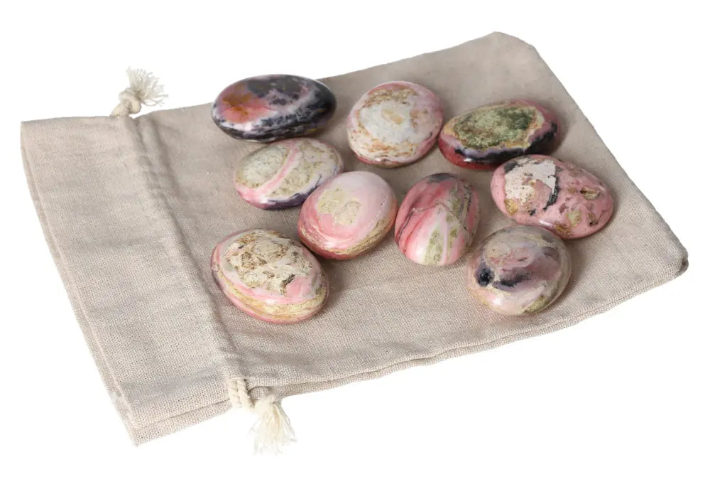 Pink Opal palmstones with soothing pastel hues, placed on a beige fabric, known for emotional healing and personal transformation.