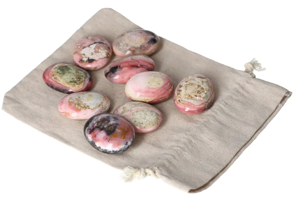 Collection of pink opal palmstones on a beige cloth, showcasing their pastel hues and smooth texture, perfect for emotional healing.