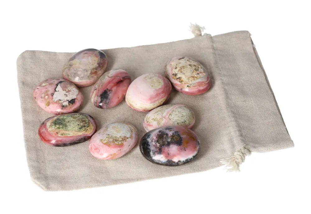 Pink Opal palmstones with pastel pink hues on a beige cloth, showcasing their smooth texture and soothing appearance for emotional healing.
