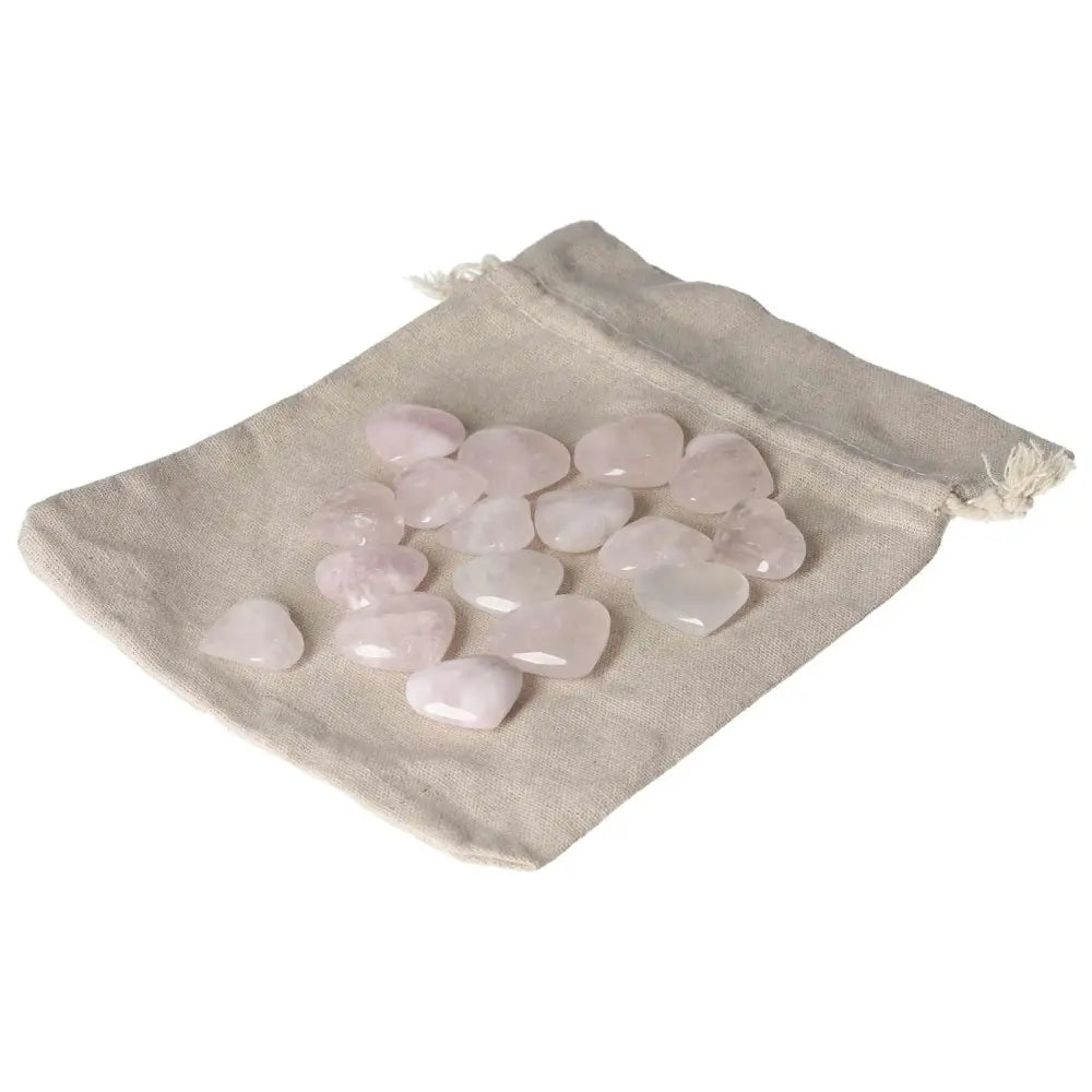 Collection of small pink quartz heart-shaped stones on a beige cloth bag