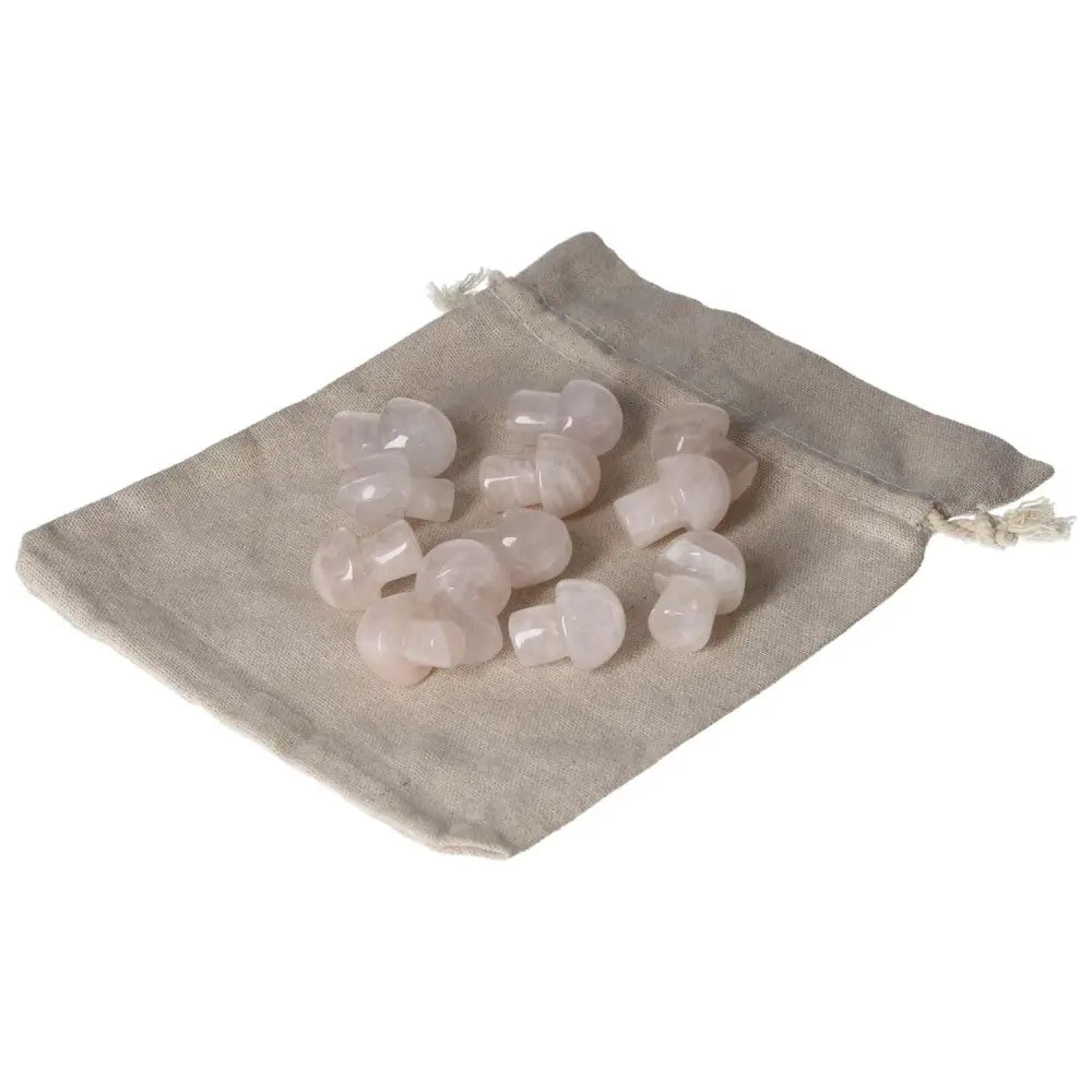Small pink quartz mushroom stones on a beige drawstring pouch, ideal for decorative and healing purposes.