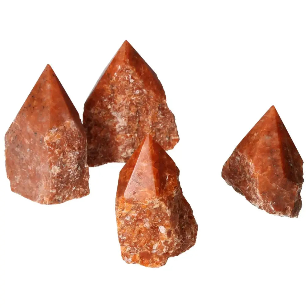 Four polished point calcite crystals in shades of orange and red, symbolizing vitality and transformation, from Sylvia Crystals.