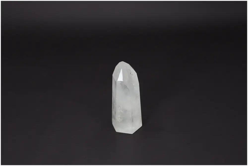 Polished Quartz Obelisk by Sylvia Crystals on dark background, showcasing its serene beauty and spiritual energy enhancement properties.