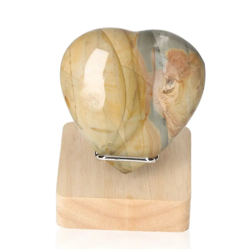 Polychrome Jasper Heart gemstone with vibrant earthy hues on a wooden stand, symbolizing emotional connection and natural beauty.