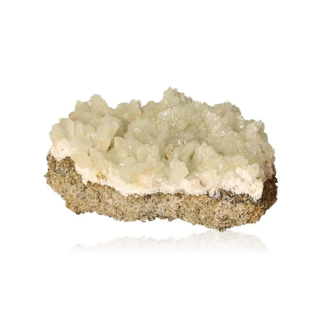 Prehnite druzy gemstone showcasing translucent pale green crystals on a stone base, known for promoting inner peace and spiritual growth.