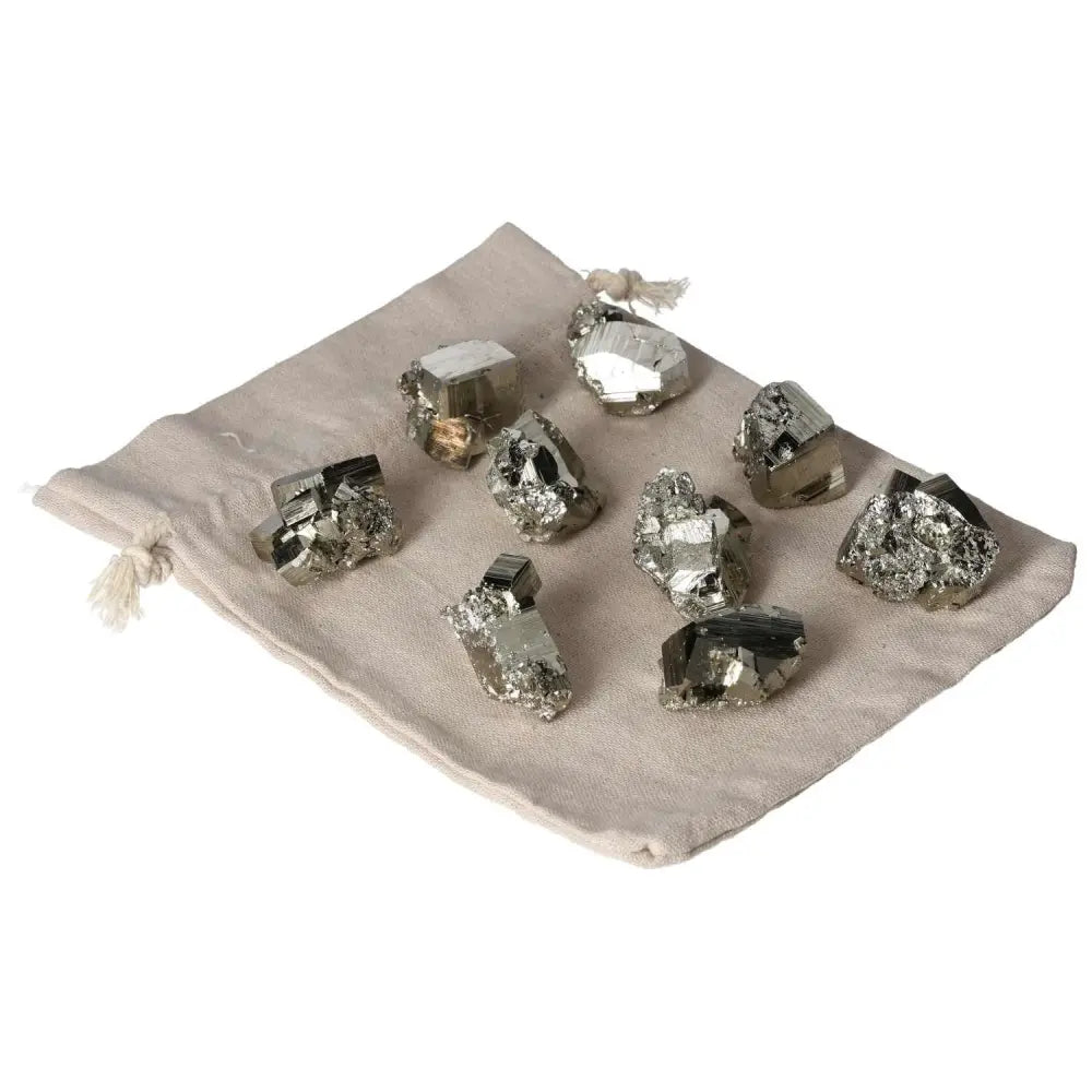 Collection of polished pyrite shapes on a cloth bag, showcasing their golden luster and grounding energy.